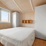 Bedroom with wooden walls, bed, and window. Two wardrobes and wall shelf.