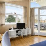 Living room with TV, window, and terrace door. Wooden floor and blue seating.