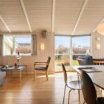 Living and dining area with wooden ceiling, windows, and modern furniture.