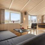 Living room with wooden walls, sofa, chair, and windows.