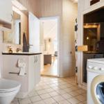 Bathroom with toilet, washing machine, and sauna entrance.