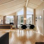 Living room with dining area, wooden floor, and wood-burning stove. Large windows provide ample daylight.