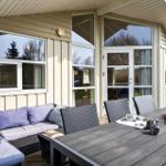 Terrace with seating group and dining table. Glass door and wooden wall visible.