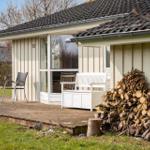 Deck with seating and woodpile in front of a house.