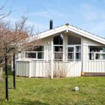 House with wooden porch and garden. Soccer ball lies on the lawn.