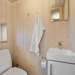 Bathroom with toilet, sink, and mirror on wooden wall
