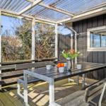 Deck with table, benches, and flowers under a roof.