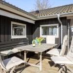 Deck with table, chairs, and flowers in front of a house with dark siding.