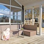 Deck with wicker sofa, table, and blankets. View of garden and house.