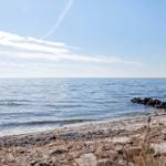 Beach with stones and calm sea under blue sky.