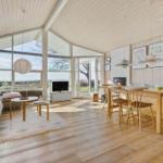 Living and dining area with wooden ceiling, large windows, and dining table with chairs.