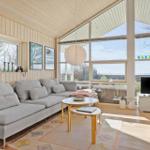 Living room with sofa, coffee table, and TV. Large windows offer a view of the lake.