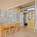 Dining area with wooden table, chairs, and wall art. Upper level with ladder and cabinet.
