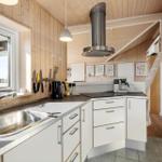 Kitchen with wooden walls, sink, stove, and range hood.