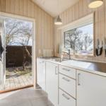 Kitchen with white cabinets, windows, and door to the garden.