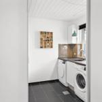 Waschraum mit Waschmaschine, Spüle und Holzregal an der Wand.