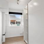 Schlafzimmer mit weißem Schrank und Fensterblick auf Dach