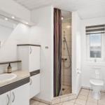 Badezimmer mit Dusche, Toilette und Waschbecken mit Spiegel.