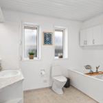 Badezimmer mit Badewanne, Toilette und Waschbecken mit Spiegel.