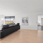 Wohnzimmer mit grauem Sofa, Holzboden und Blick auf das Feld.