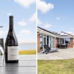 Wein und Gläser auf Tisch. Ferienhaus mit Terrasse, Liegestühlen und Garten.