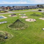 Grüner Spielplatz mit Sandkästen, Klettergerüsten und Bootsanlegestelle am See