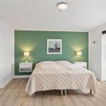 Schlafzimmer mit grüner Wand, Bett, Nachttischen und Fenster.