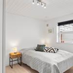 Schlafzimmer mit Bett, Nachttisch und Fenster mit Blick auf Terrasse.