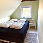Schlafzimmer mit Doppelbett, Fenster und Nachttisch.