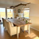 Esszimmer mit Holztisch, cremefarbenen Stühlen und rustikaler Deckenleuchte.