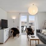 Wohnzimmer mit Sofa, Fernseher und Blick auf Balkon