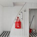 Eingangsbereich mit schwarz-weißem Fliesenboden und roter Tasche an der Wand.