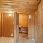 Holzsauna mit Sitzbänken und Tür. Fliesenboden und Holzwände.