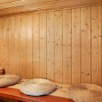 Sauna mit Holzwand, Sitzbank und geflochtenen Kissen.