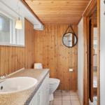 Badezimmer mit Holzwand, Waschbecken und Toilette.