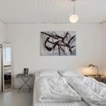 Schlafzimmer mit Bett, Wandbild und Kleiderständer.