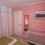 Schlafzimmer mit Babybett, Kleiderschrank und Wandbild.