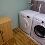 Wäschetrockner und Waschmaschine in einem Raum mit Holzboden und Schrank.