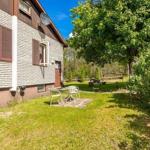 Haus mit Garten, Terrasse und Sitzgelegenheit unter Bäumen.