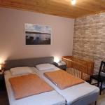 Zimmer mit Doppelbett, Kinderbett und Holzdecke.