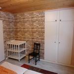 Schlafzimmer mit Holzdecke, Ziegelwand, Kleiderschrank und Babywanne.