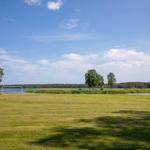 Grünes Feld mit Fußballtoren am See unter blauem Himmel
