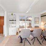 Dining room with wooden table, gray chairs, and glass door to garden