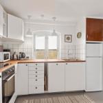 Kitchen with white cabinets, wooden countertop, and window with view.