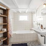 Bathroom with bathtub, sink, and wooden shelf.