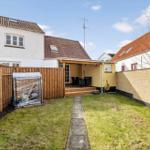 Backyard with terrace, barbecue area, and garden shed. Wooden fence and brick wall surround the space.
