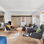 Living room with sofa, two chairs, and wooden floor. Connected dining area with table and chairs.