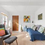 A room with a sofa, an armchair, and artwork on the walls.