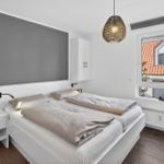Schlafzimmer mit Doppelbett, Fenster und Deckenleuchte.