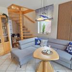 Wohnzimmer mit Sofa, Tisch und Glaswand. Holztreppe und Fenster mit Pflanze.